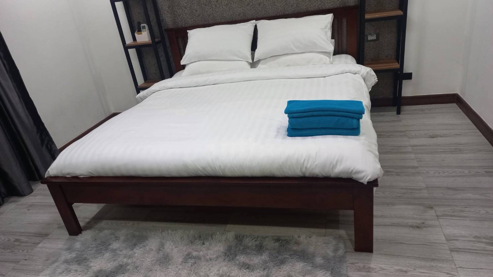 Real double bed with white linen and teal towels at Flame